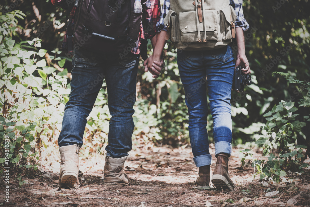 Closeup image of a lover couple holding hands and trekking in a tropical forest together Closeup image of a lover couple holding hands and trekking in a tropical forest together