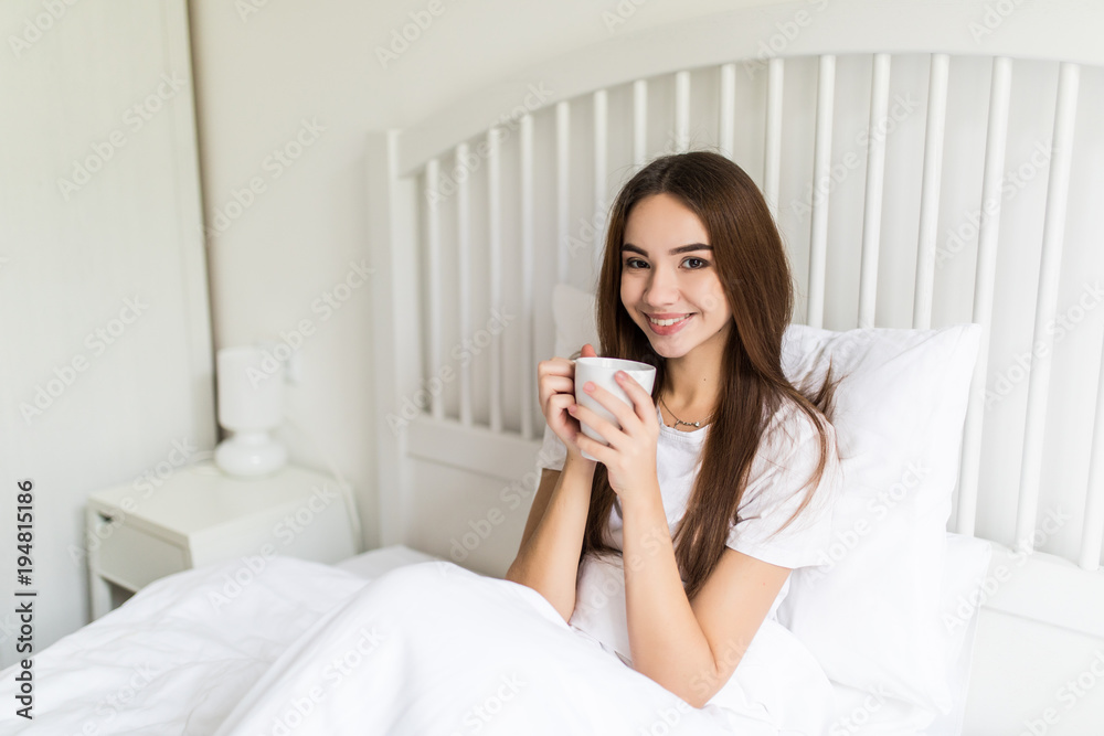 Beautiful young woman at her bedroom drinking tea in the morning. Beautiful young woman at her bedroom drinking tea in the morning.