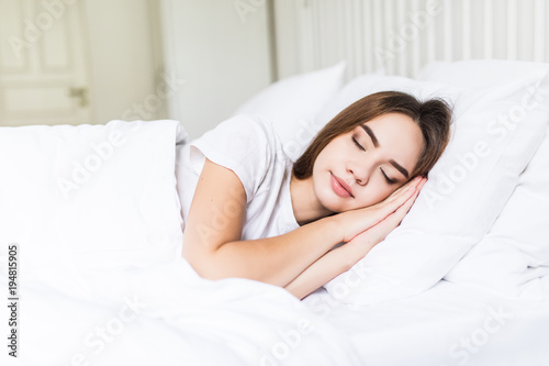 Young beautiful woman sleeping in her bed and relaxing in the morning