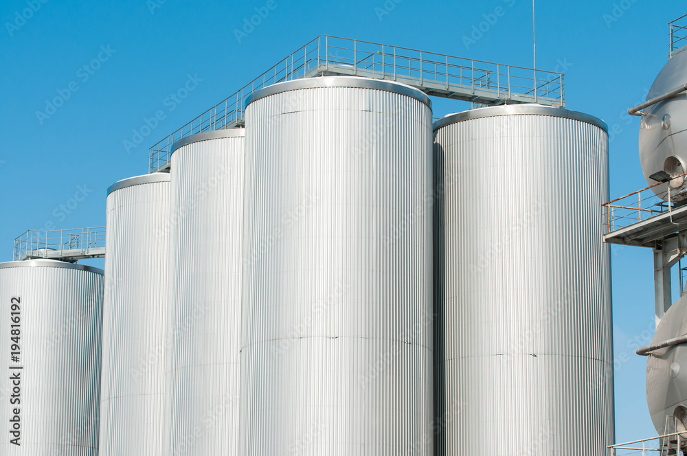 Huge barley tanks close up shot with blue sky background.