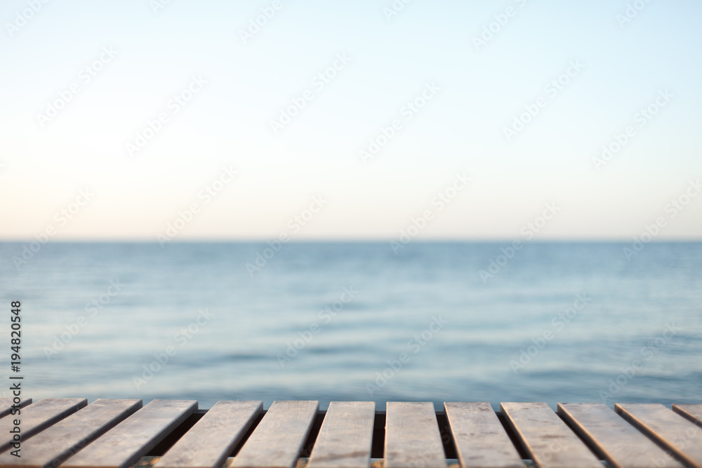 Wooden table in front of blurred sea background.