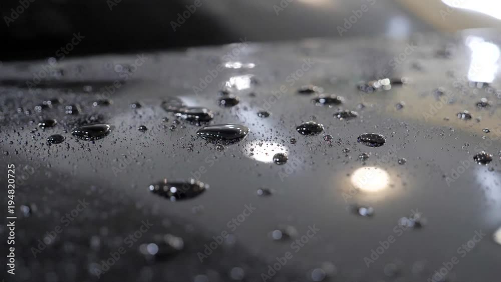 Water drops slowly flow on a black car after car wash slow motion. Water drops slowly flow on a black car after car wash slow motion.