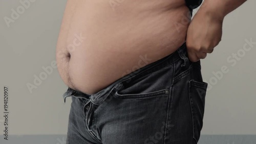 overweight man closeup of belly trying to put up jeans Trying fasten a button