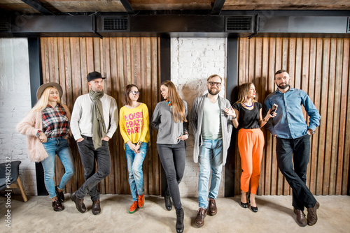 Young people dressed casually standing together near the wooden wall background