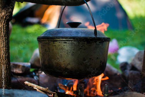 Old travel cauldron over the fire against the tent