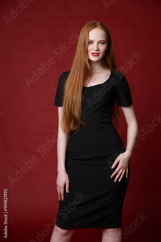 Portrait of a beautiful red-haired girl on a red background.