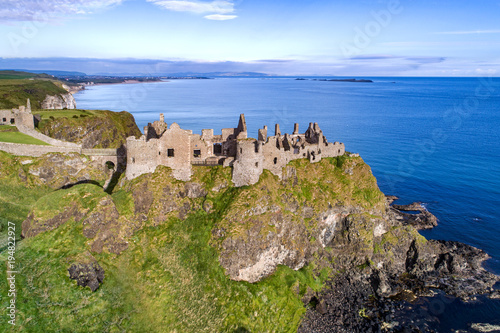 Ruins of medieval Dunluce Castle, cliffs, bays and peninsulas. Northern coast of County Antrim, Northern Ireland, UK. Aerial view.