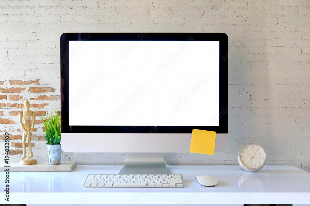 Fototapeta premium Blank screen on the desktop computer with house plant and office supplies, mock up