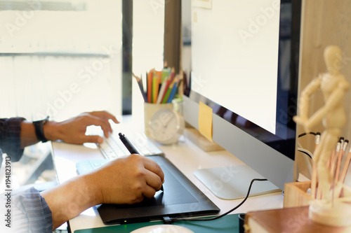 Cropped shot of Graphic designer using graphics tablet and modern desktop computer to do his work at desk