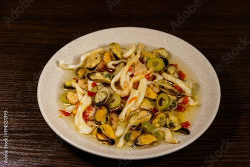 Seafood salad with shrimp, squid and mussels on wooden table