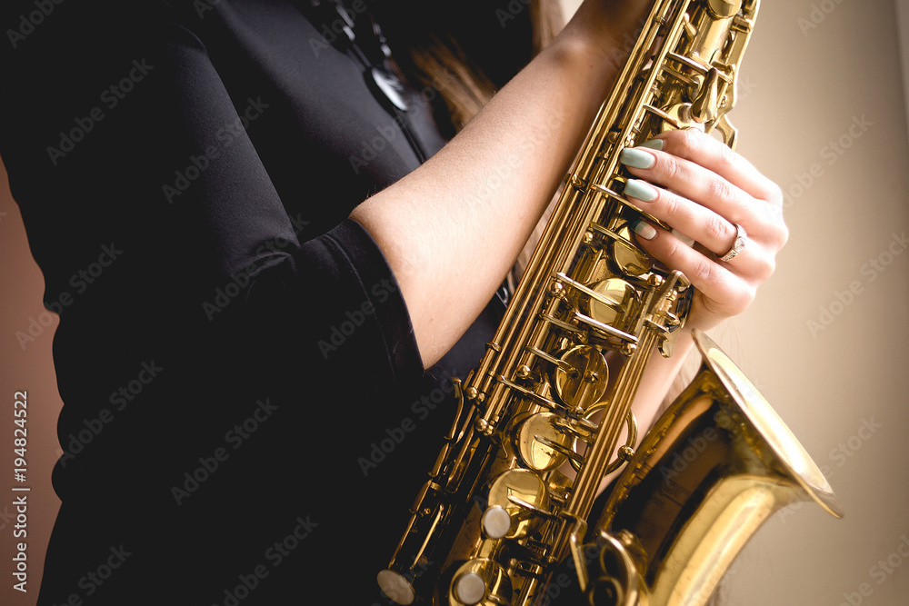 Obraz premium gold saxophone in the hands of girl in black