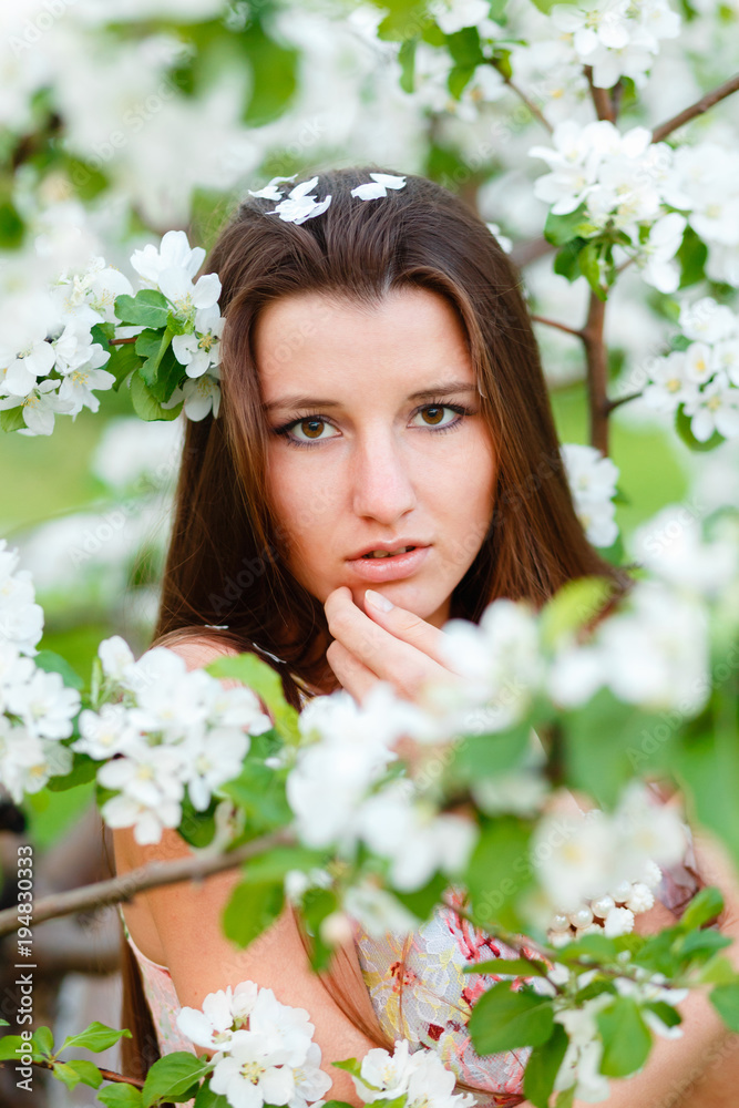 Portrait of a young beautiful woman posing among blooming Apple trees. Girl with long hair posing among the flowers. Close-up with space for text. Portrait of a young beautiful woman posing among blooming Apple trees. Girl with long hair posing among the flowers. Close-up with space for text.
