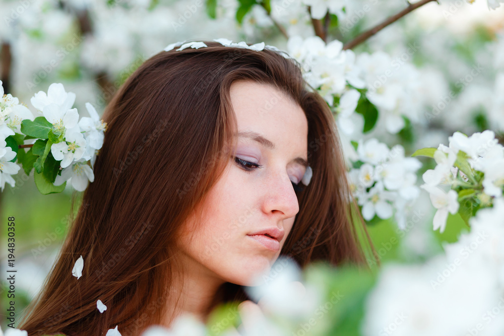 Portrait of a young beautiful woman posing among blooming Apple trees. Girl with long hair posing among the flowers. Close-up with space for text. Portrait of a young beautiful woman posing among blooming Apple trees. Girl with long hair posing among the flowers. Close-up with space for text.