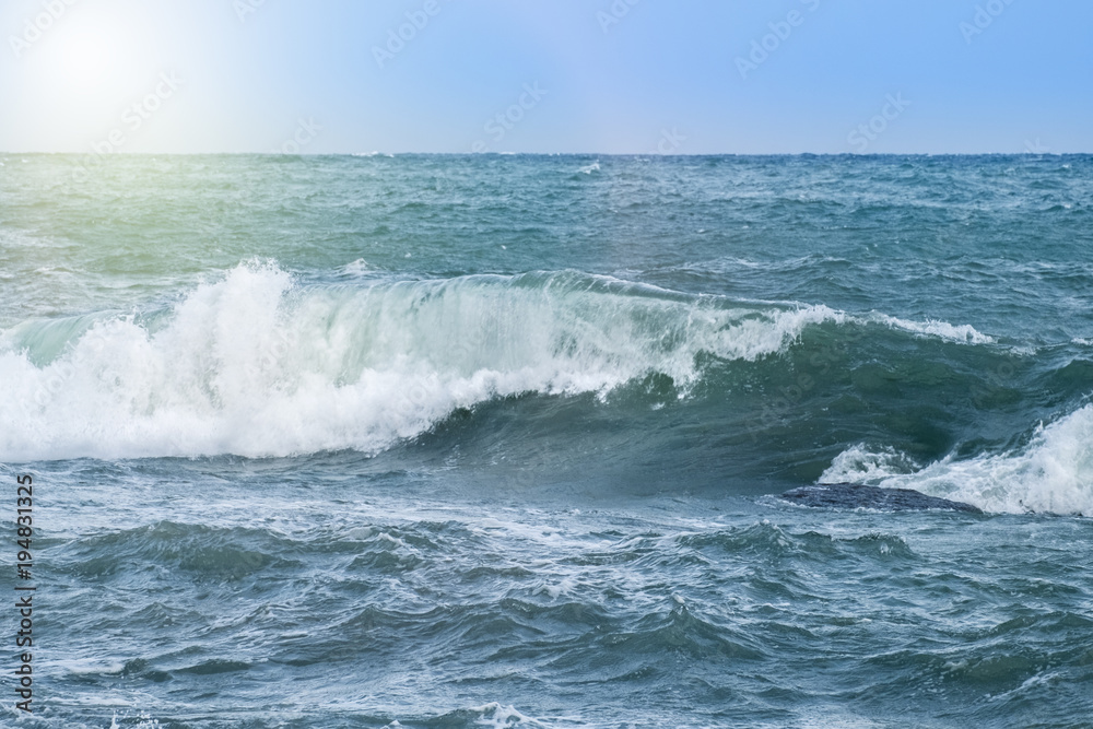 Beautiful big waves of the sea in the summer bright blue, turquoise colors in the early morning in sun light on a pure blue sky.
