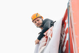 Industrial climber hangs a poster on a billboard
