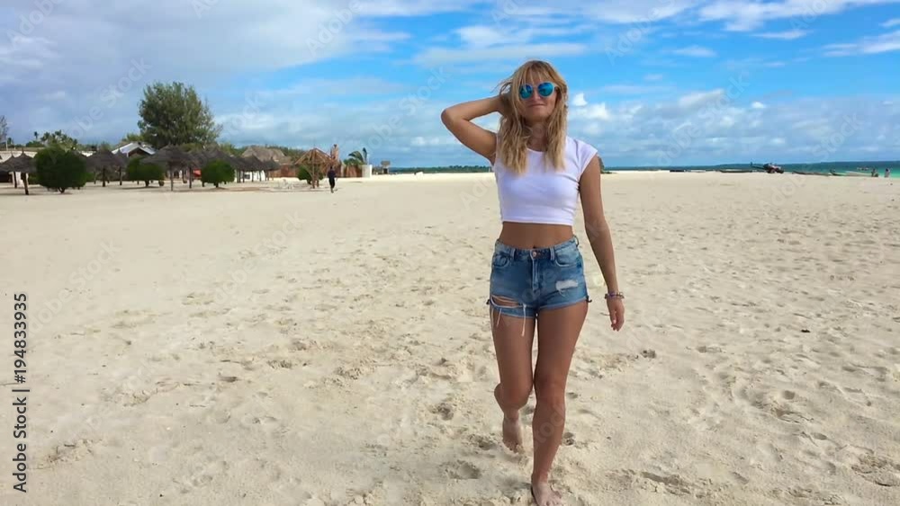 A young slender attractive girl walks along the beach of Zanzibar and flirts with a camera near the Indian Ocean on a hot, sunny day. Slow motion against a virgin nature. A young slender attractive girl walks along the beach of Zanzibar and flirts with a camera near the Indian Ocean on a hot, sunny day. Slow motion against a virgin nature.