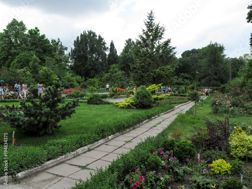 Ukraine, Zaporizhia - June 24, 2017: Excursion on Zaporizhzhya city children's botanical garden. Beautiful spring - summer garden with stone paths and flower beds and people admire colorful flowers