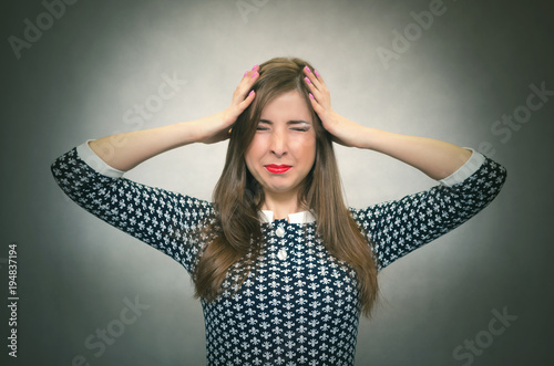 Overworked woman in stress is holding her head by her hands and try to solve her problem isolated on gray background. Deprsession. Debts concept.