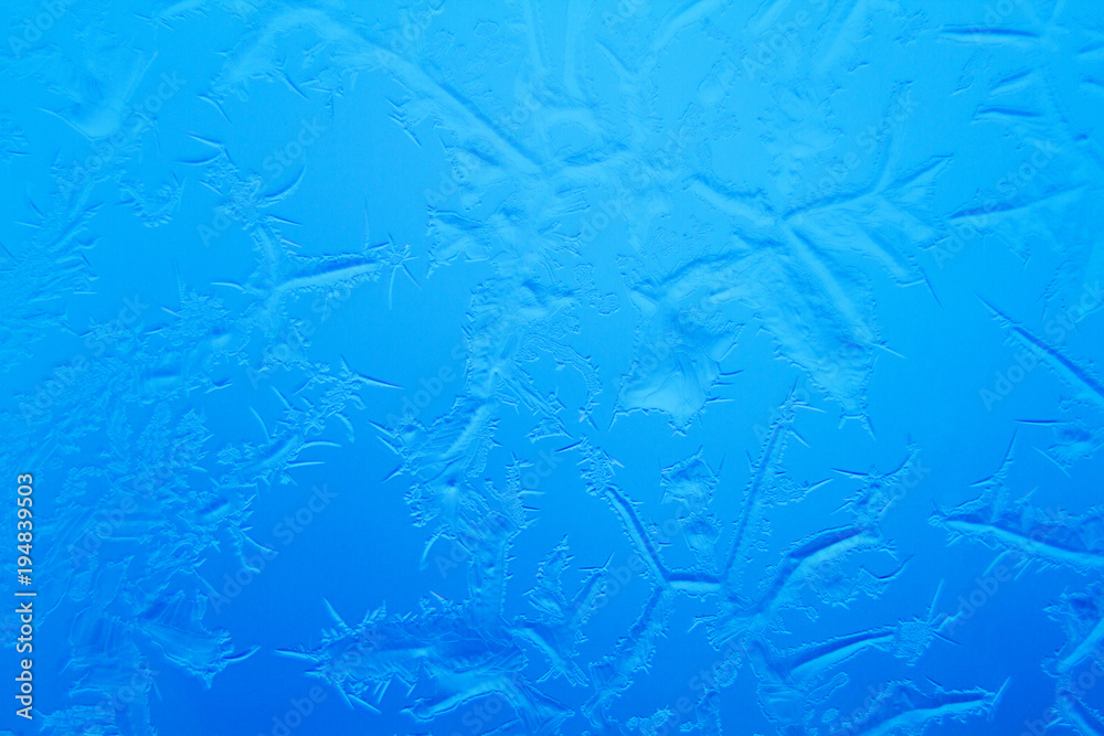 Frosty patterns on window glass on blue background