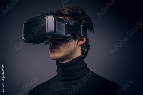 Portrait of a man wearing virtual reality device isolated on a d © Fxquadro