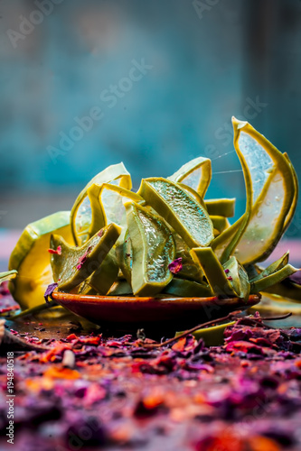 Close up of Ayurvedic face pack's ingredients i.e  cucumber and Aloe Vera gel with rose petals on a wooden surface in dark Gothic colors.It helps in brighting the skin tone. photo