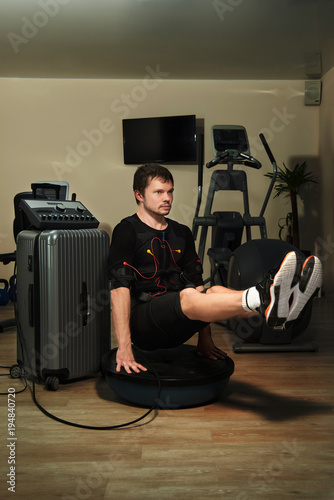Man in EMS suit doing L-Sit plank on bosu ball