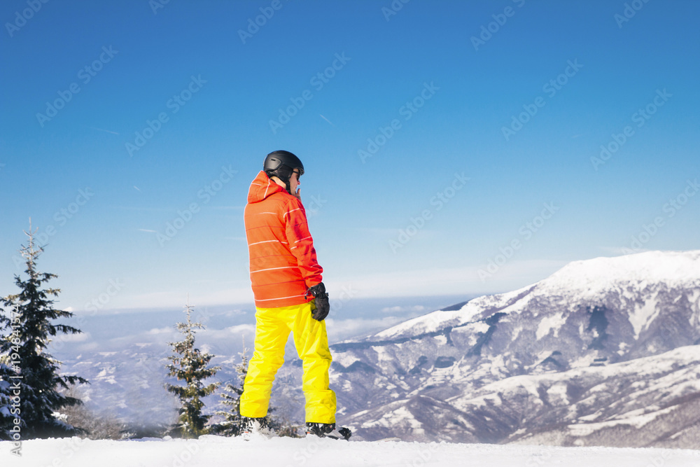 Snowboarder standing in mountains