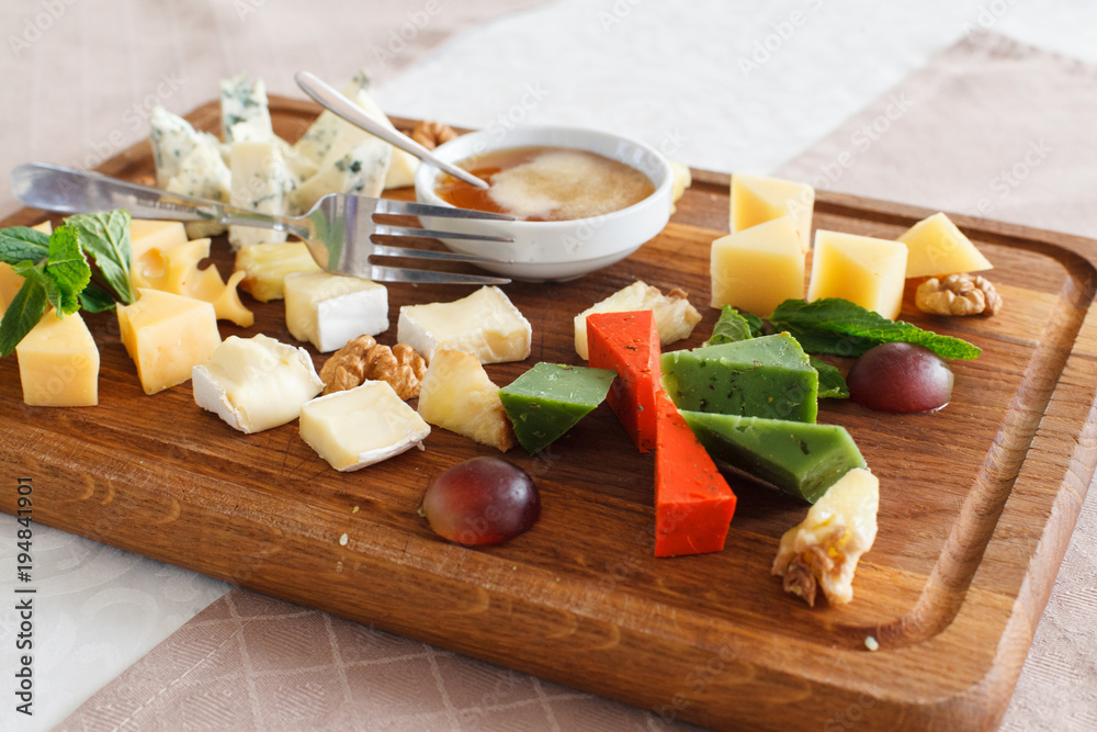 Cheese plates served with grapes, jam and nuts. Wooden desk