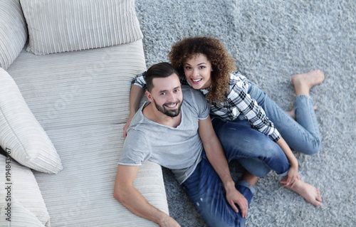 young couple sitting on the carpet in the new living room
