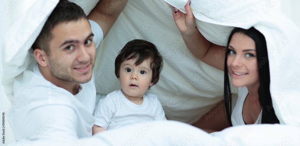 Families with children in bed under a blanket Families with children in bed under a blanket