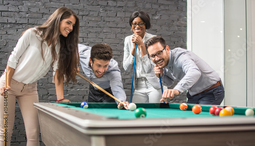 Fotografie Cheerful business people playing billiards during office break.
