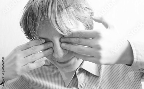 Teen boy closes his eyes with his hands photo