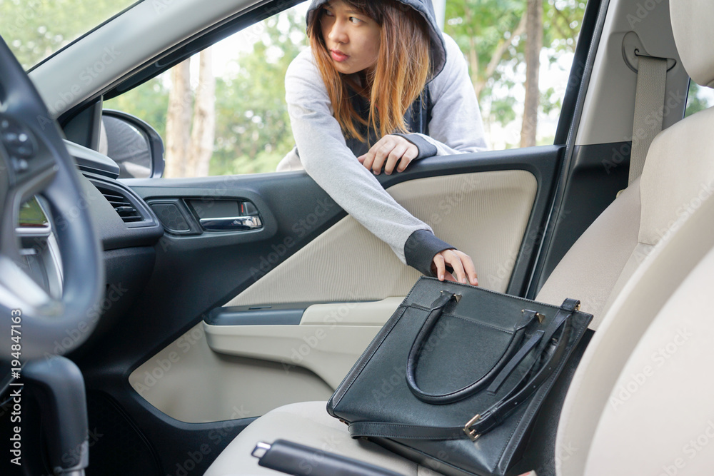 Woman burglar steal a shoulder bag through the window of car - theft concept.