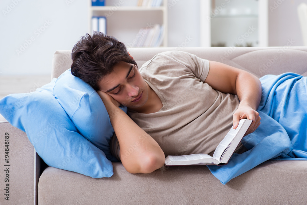 Young student man preparing for college exams in bed with book Young student man preparing for college exams in bed with book