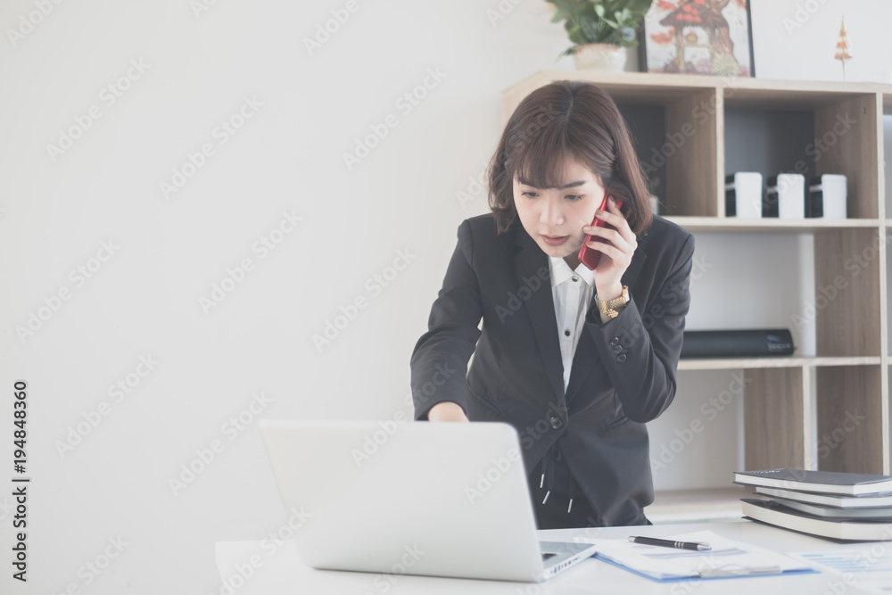 young beautiful asian woman talking on her phone with a client young beautiful asian woman talking on her phone with a client