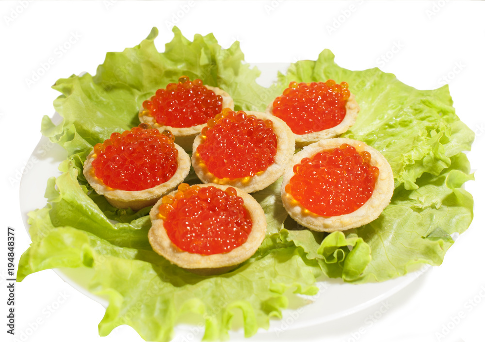 Red caviar in tartlets on lettuce leaves. Isolated white background. The view from the top.