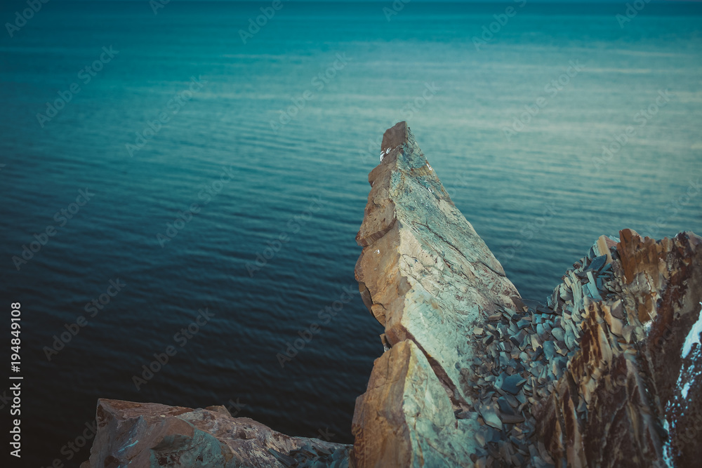Sharp rocks over water. Blue toned image.