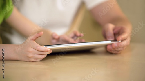 Hands of little girl typing on tablet touchscreen, father and daughter using app