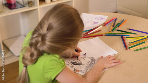 Little girl drawing stranger from her nightmare with black pencil, child fears