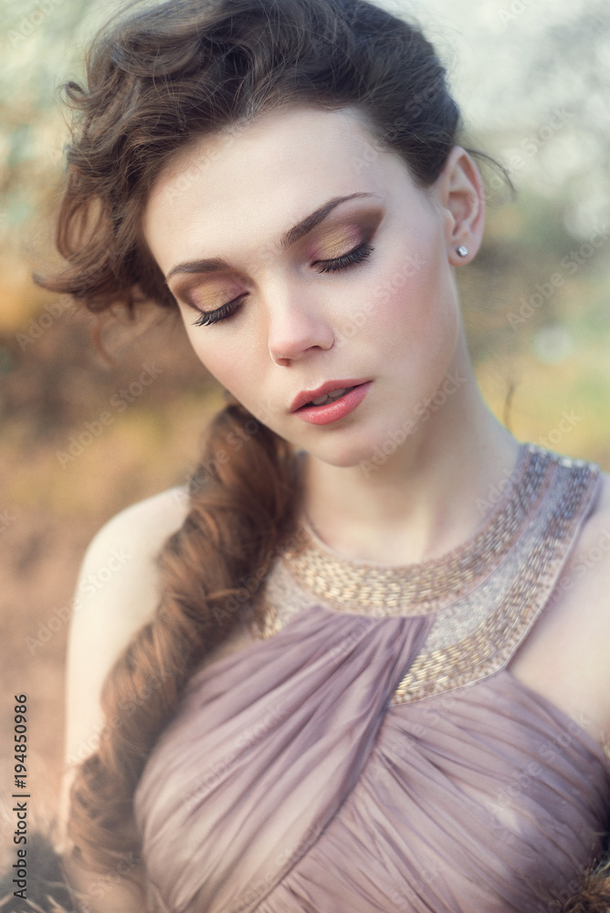 Naklejka premium Portrait of a Young woman in liliat dress in a park. Glamour fashion bride concept