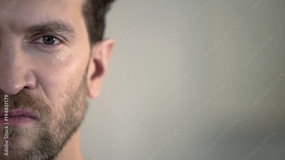 Half face of aggressive man looking with hatred into camera, domestic tyrant Half face of aggressive man looking with hatred into camera, domestic tyrant