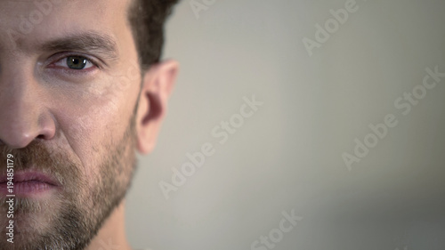 Half face of aggressive man looking with hatred into camera, domestic tyrant