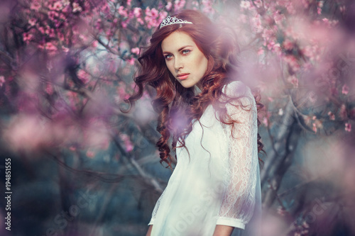 Beautiful young woman in pink peach garden. Fashion concept
