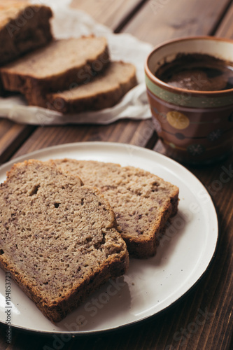 Banana bread and cup of coffe on wooden background. Breakfast concept.