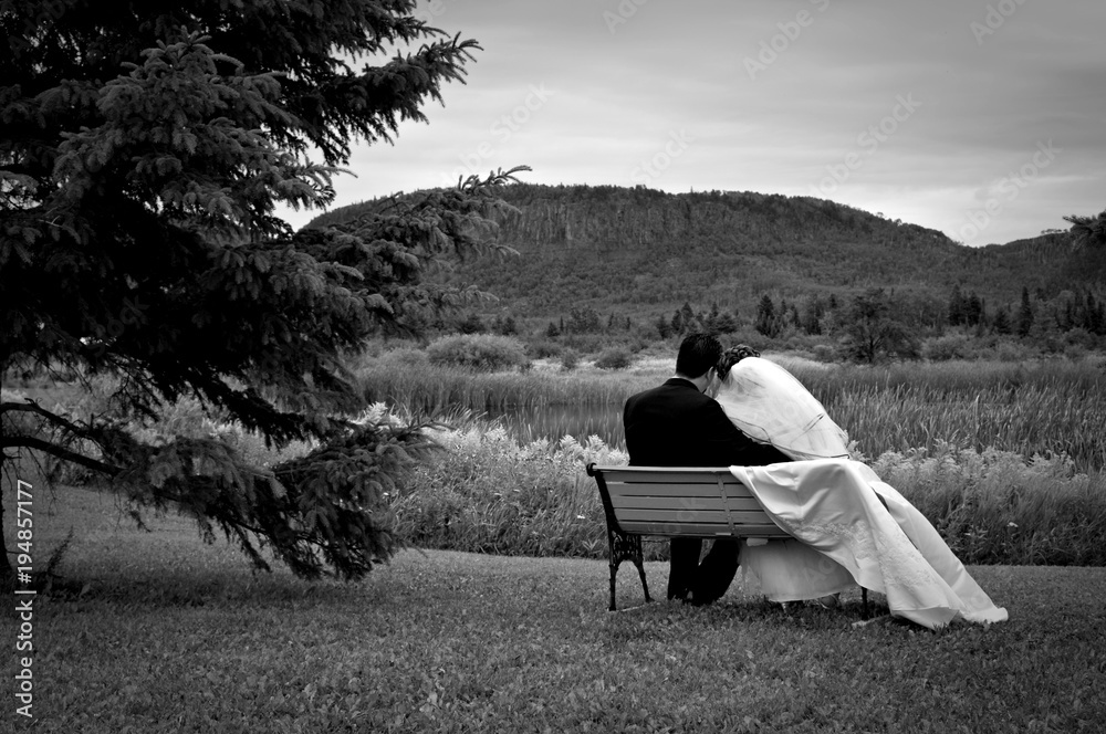 BRIDE AND GROOM ON BENCH IN FRONT OF NORWESTER MOUNTAINS B&W