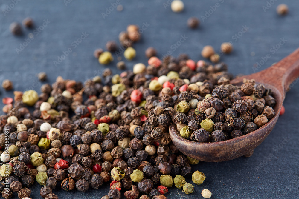 Top view on composition of peppercorns in wooden spoon on dark background, close-up. Top view on composition of peppercorns in wooden spoon on dark background, close-up.