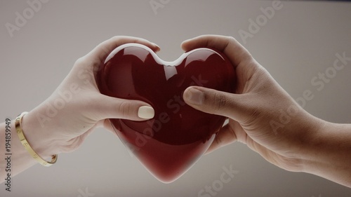 the hands of men and women holding the heart on grey