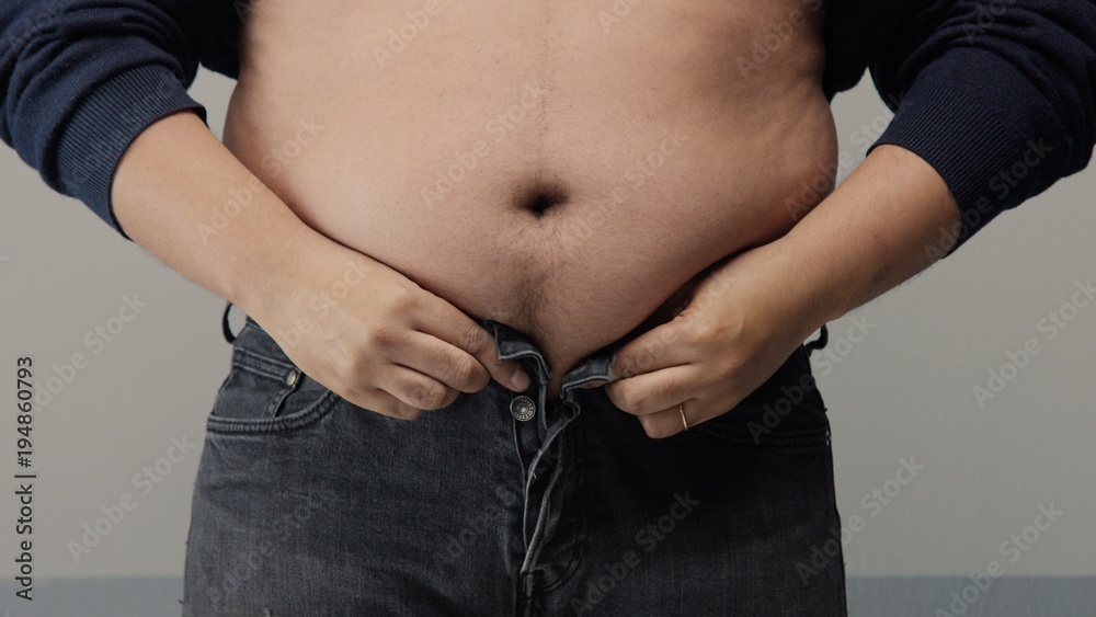 Naklejka premium overweight man closeup of belly side view. put up shirt and pinch and clap a belly