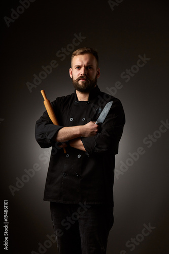 Chef cook holds a knife over dark grey background
