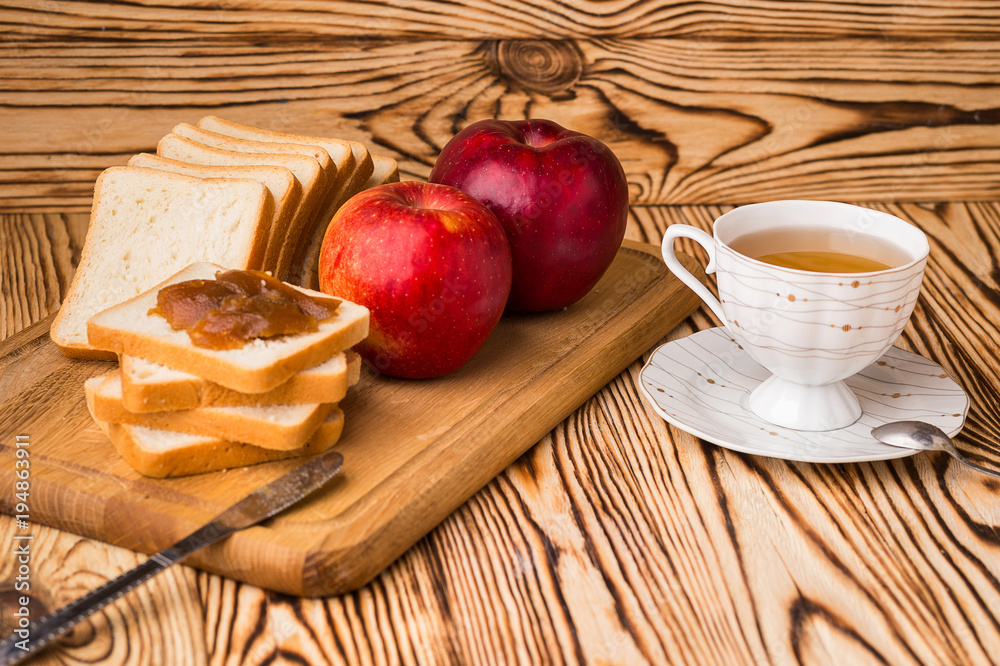 Breakfast toasts with jam on plate and cup of tea on wooden background